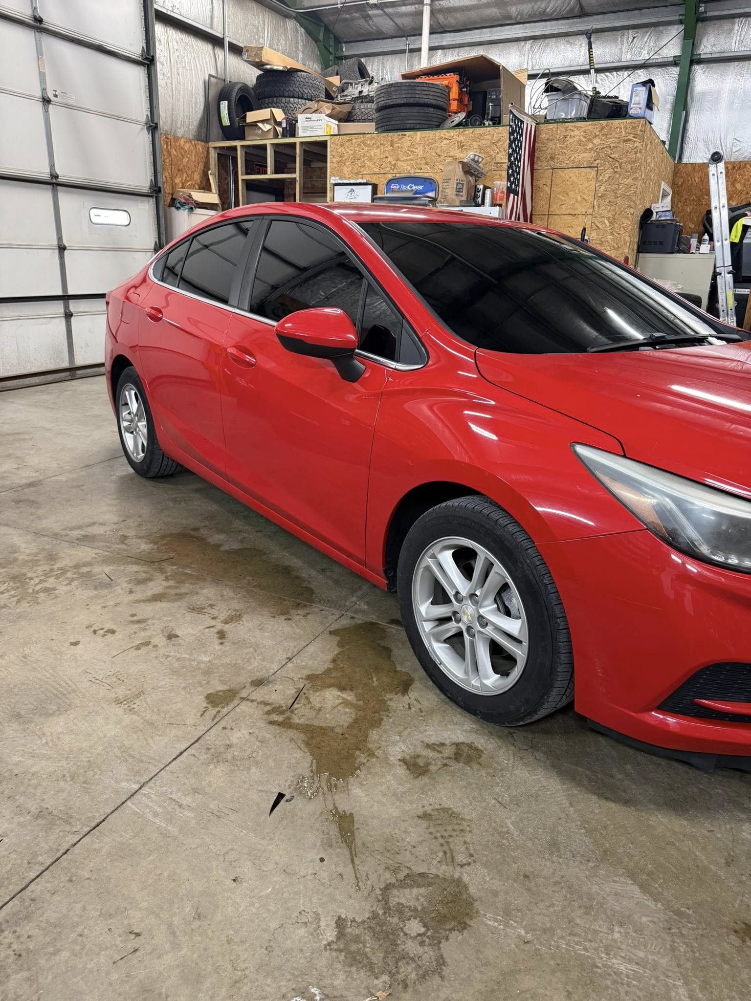 Red Chevrolet Cruze sedan with window tint, passenger-side view in the shop