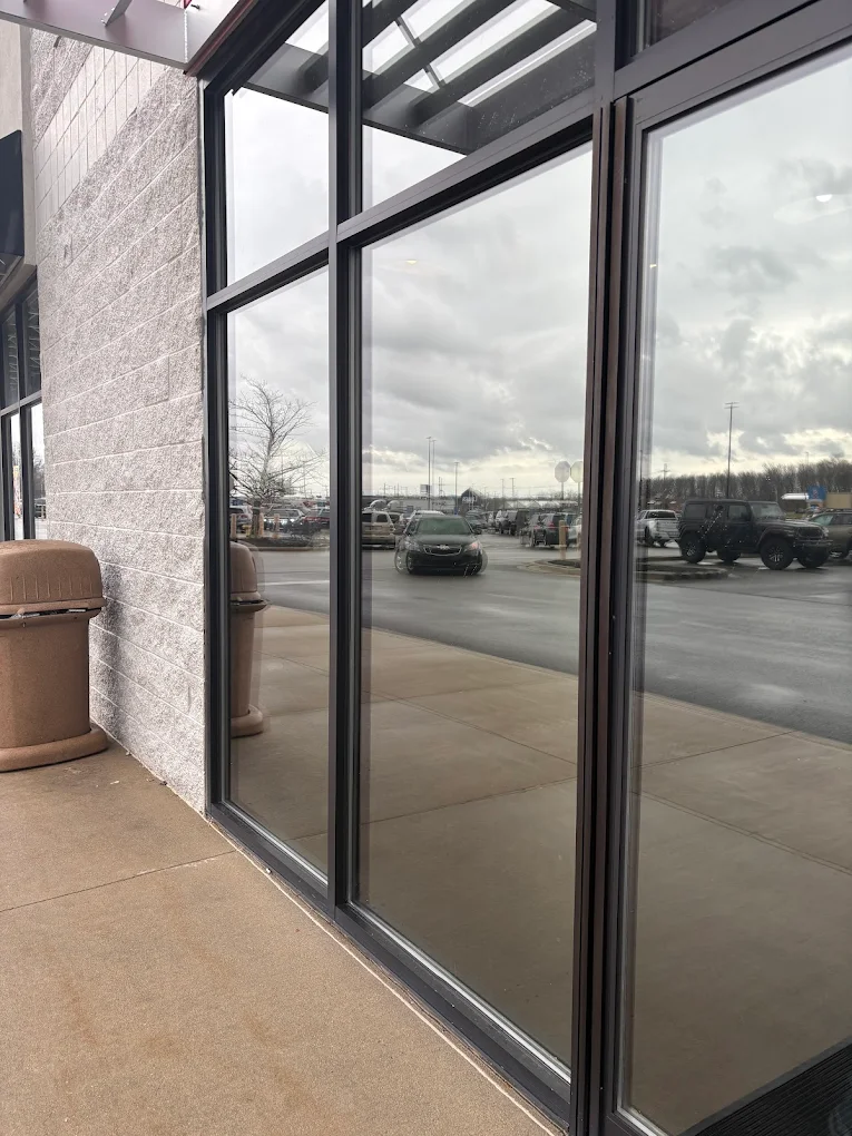 Storefront windows with commercial solar film installed, reflecting parking lot and sky
