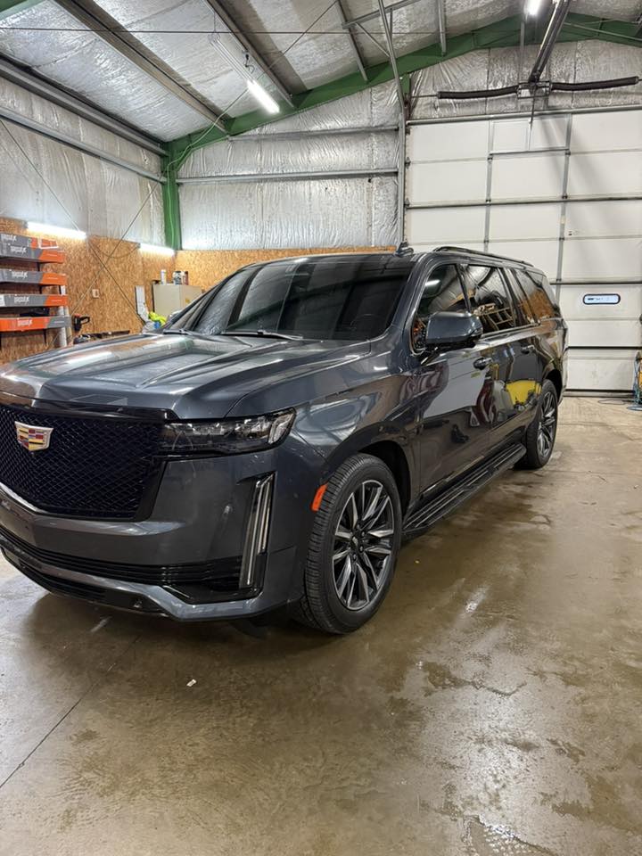 Dark gray Cadillac Escalade with darkly tinted windows freshly installed, driver-side view