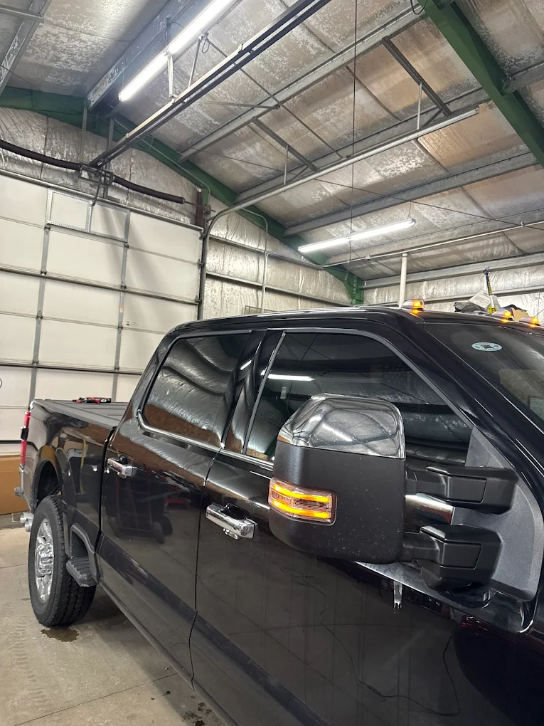 Black Ford F-150 with tinted windows and extended tow mirrors, dramatic side profile