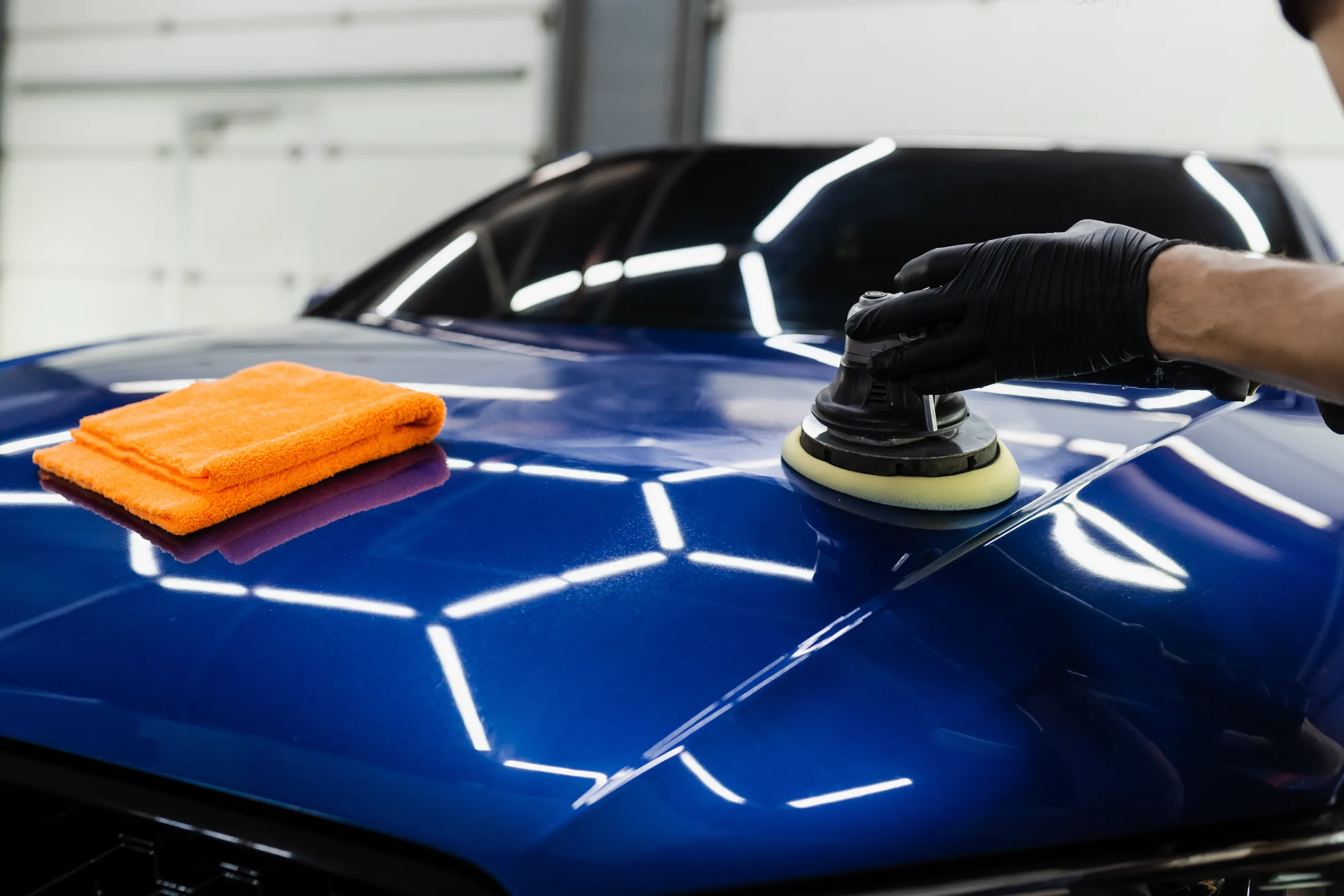 Ceramic coating being machine-applied to a glossy blue car hood